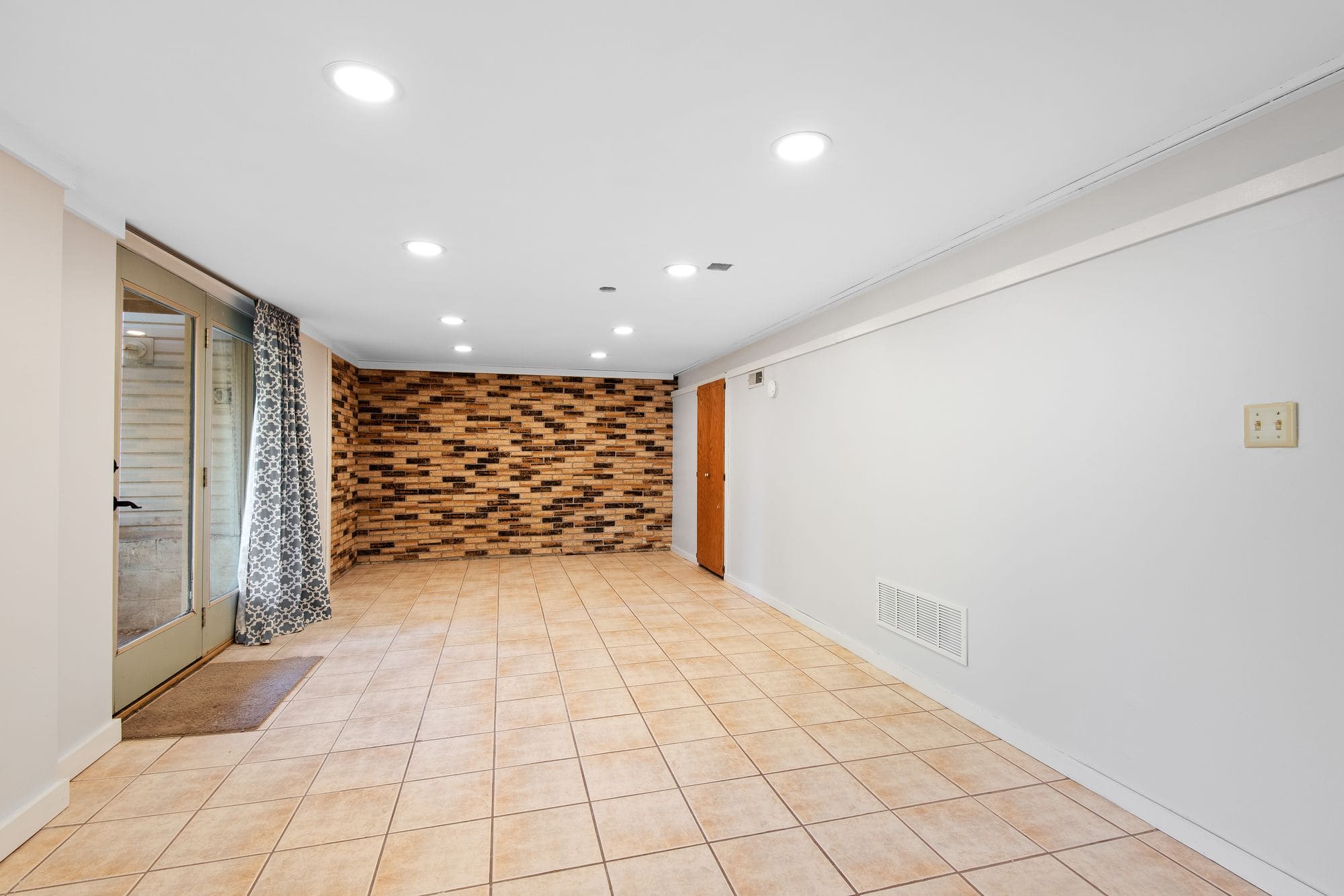 Finished lower-level room with a brick accent wall, shown as representative remodeling imagery